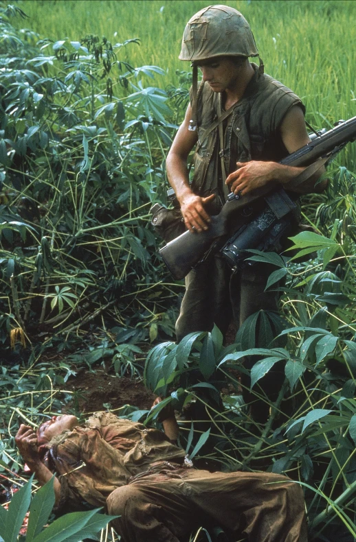 a man in camouflage holding his rifle while kneeling down