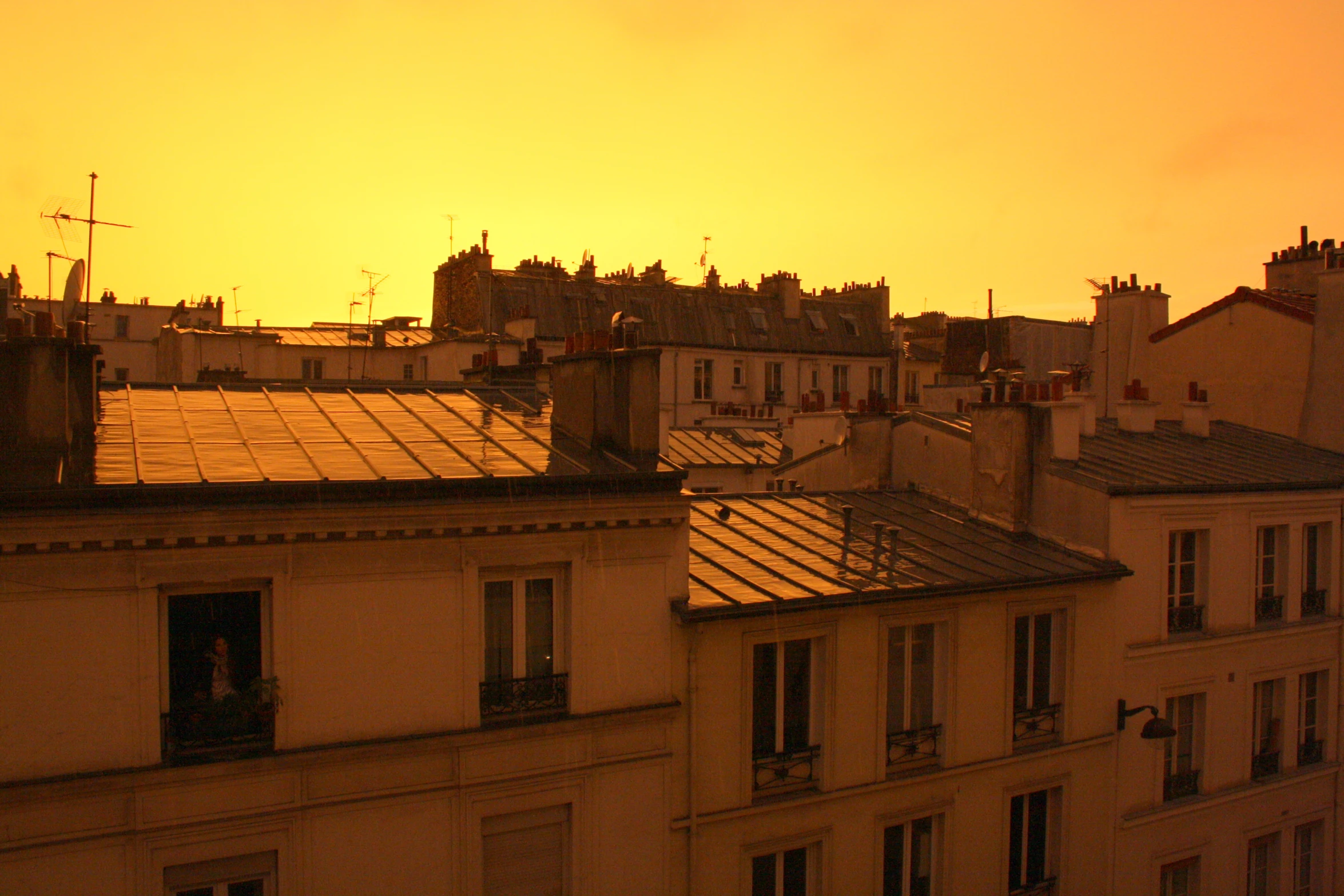 an orange sky at sunset with roofs in a city