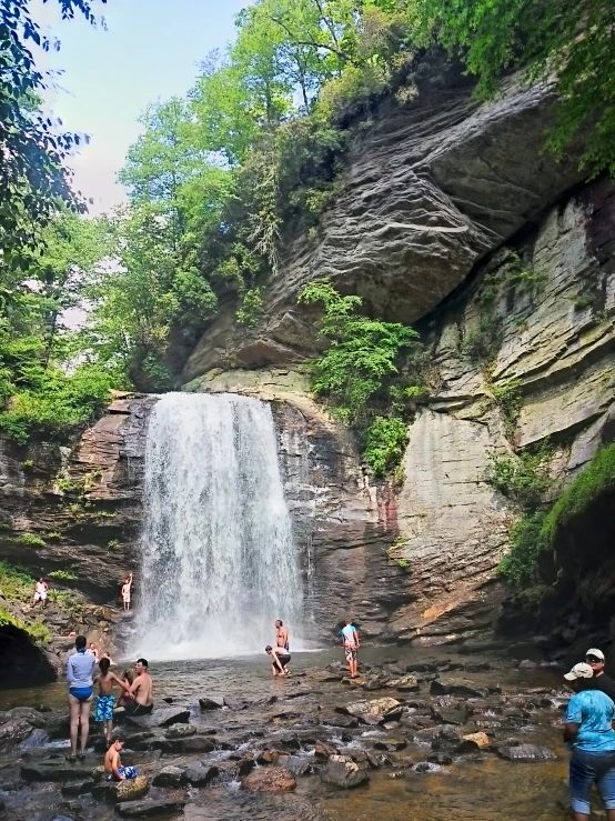 some people at the base of a waterfall and one is climbing up