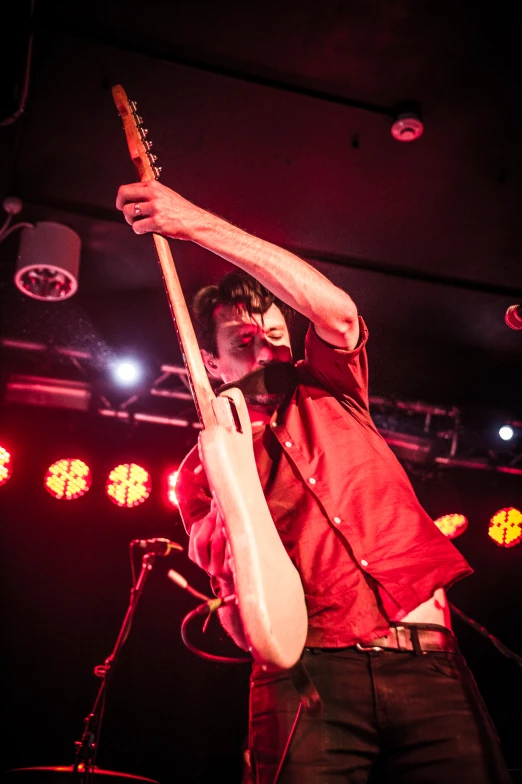 a male in a red shirt is playing the guitar