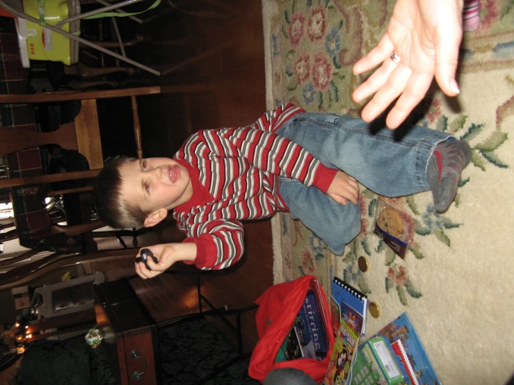 a boy is sitting on the floor holding a phone