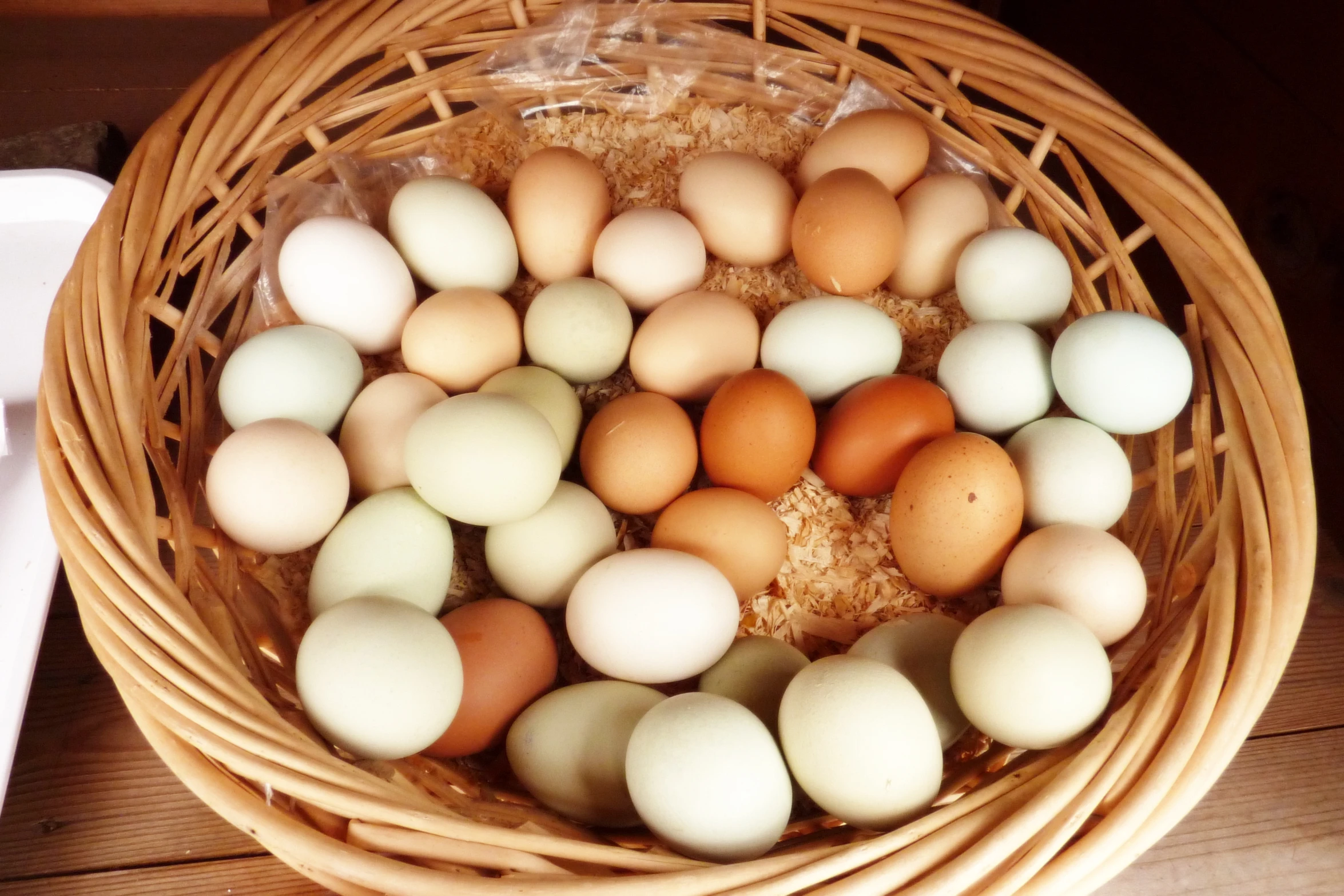 some eggs sit inside a basket on a wooden surface