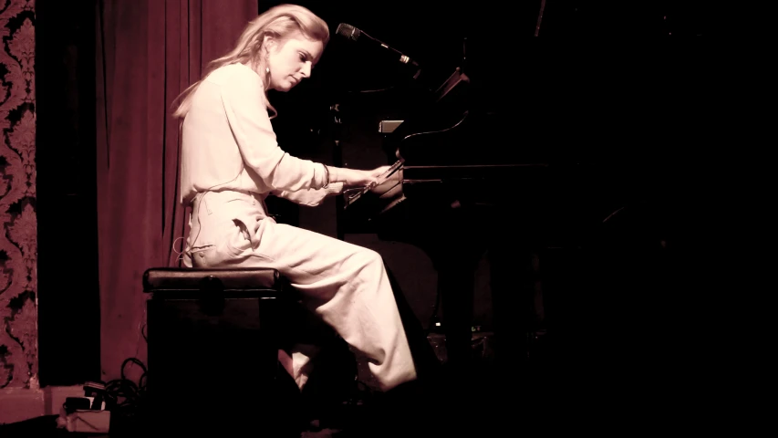 a woman playing the piano at a dimly lit stage