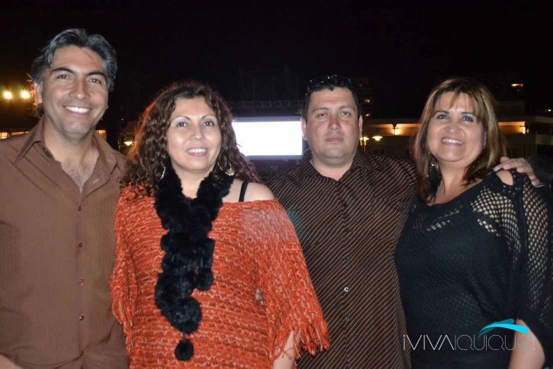 three adults are standing together at night