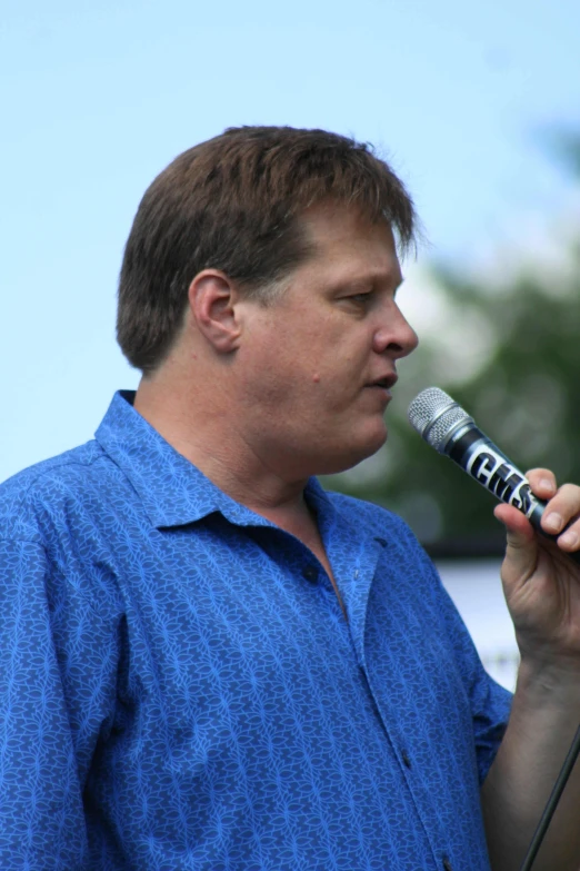 a man is holding a microphone with a blue shirt