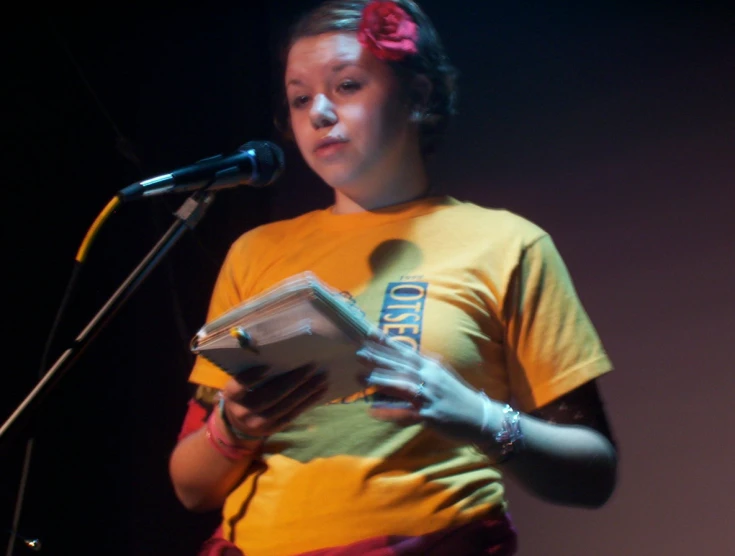 a woman reads from her own book on stage