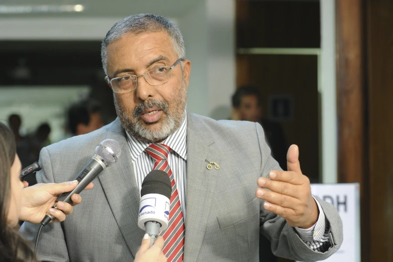 man talking on microphone with two people behind him