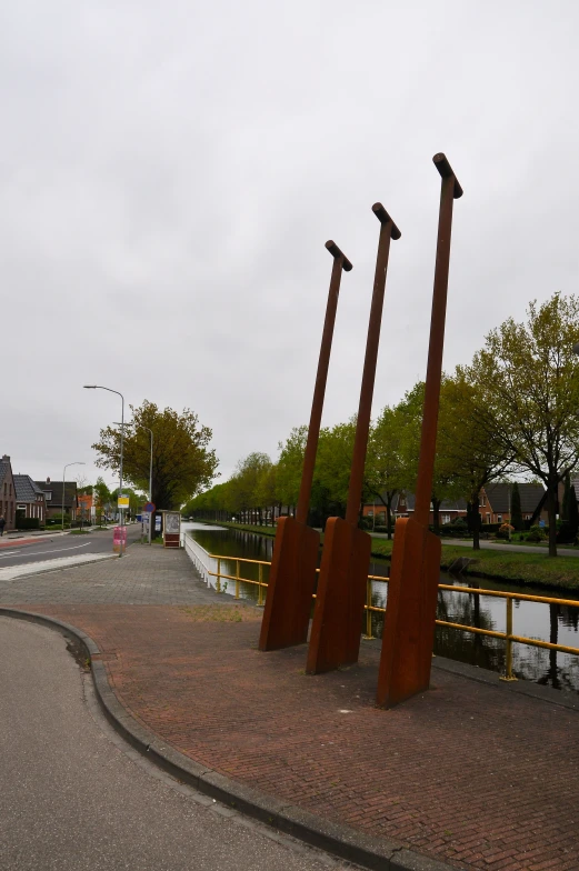 three tall metal sculptures next to a road