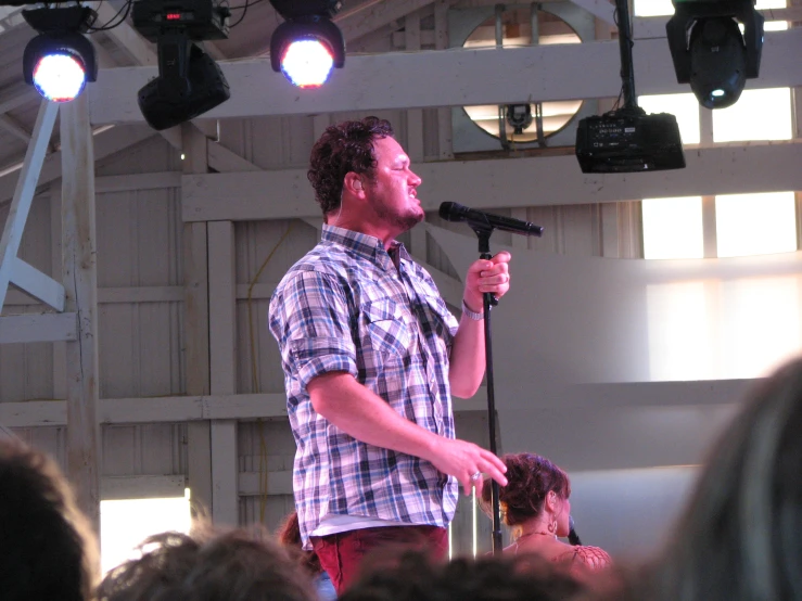 man standing at microphone in front of stage lighting and people