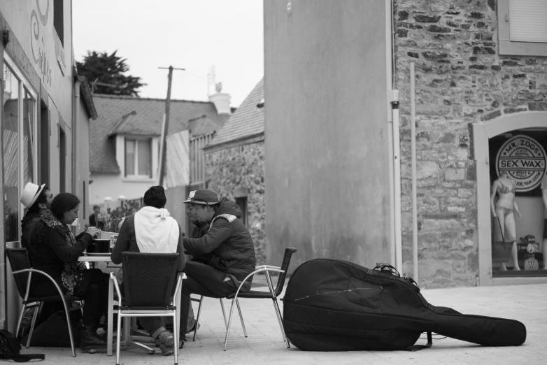 a group of people sit around eating outside on chairs