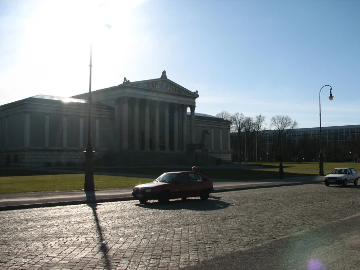 a car parked on the street of a city with large columns