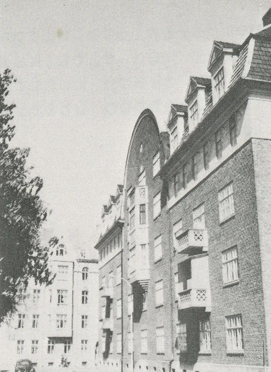 a man in black and white walking past a building