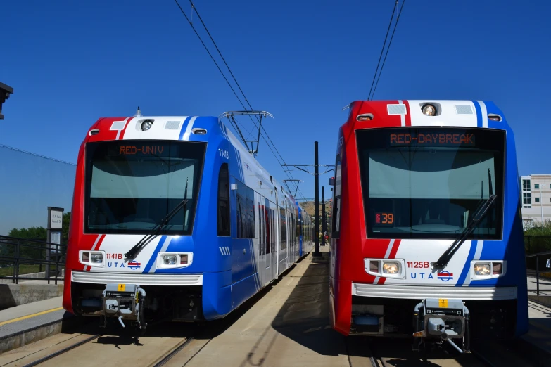 two red, white and blue trains parked next to each other