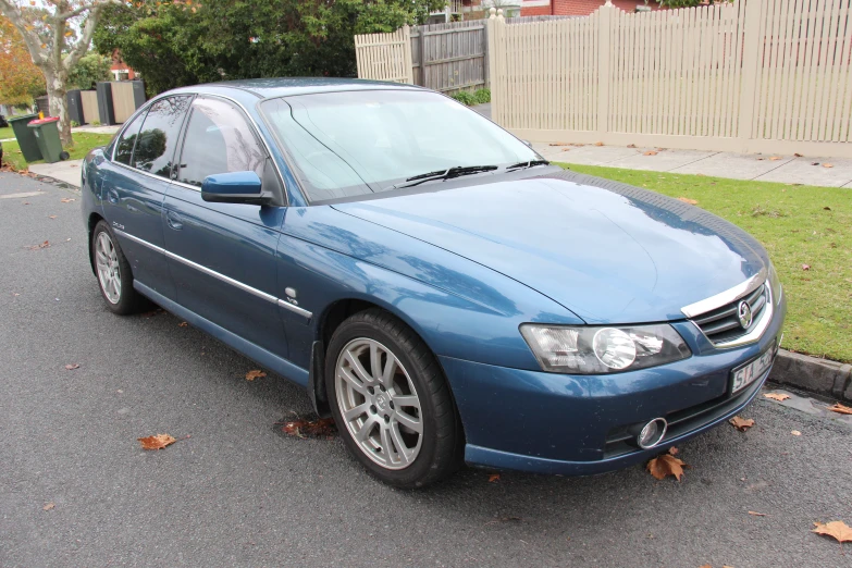 a blue car parked on a street in front of a home