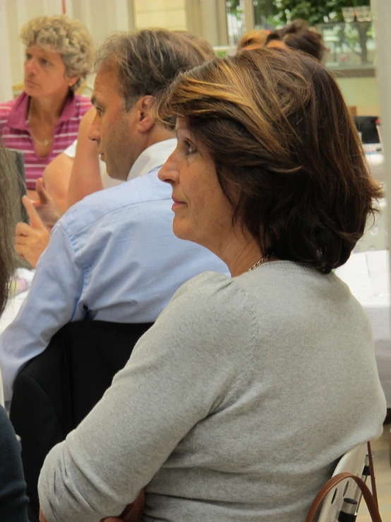 there are people sitting in a room with one woman holding a cell phone