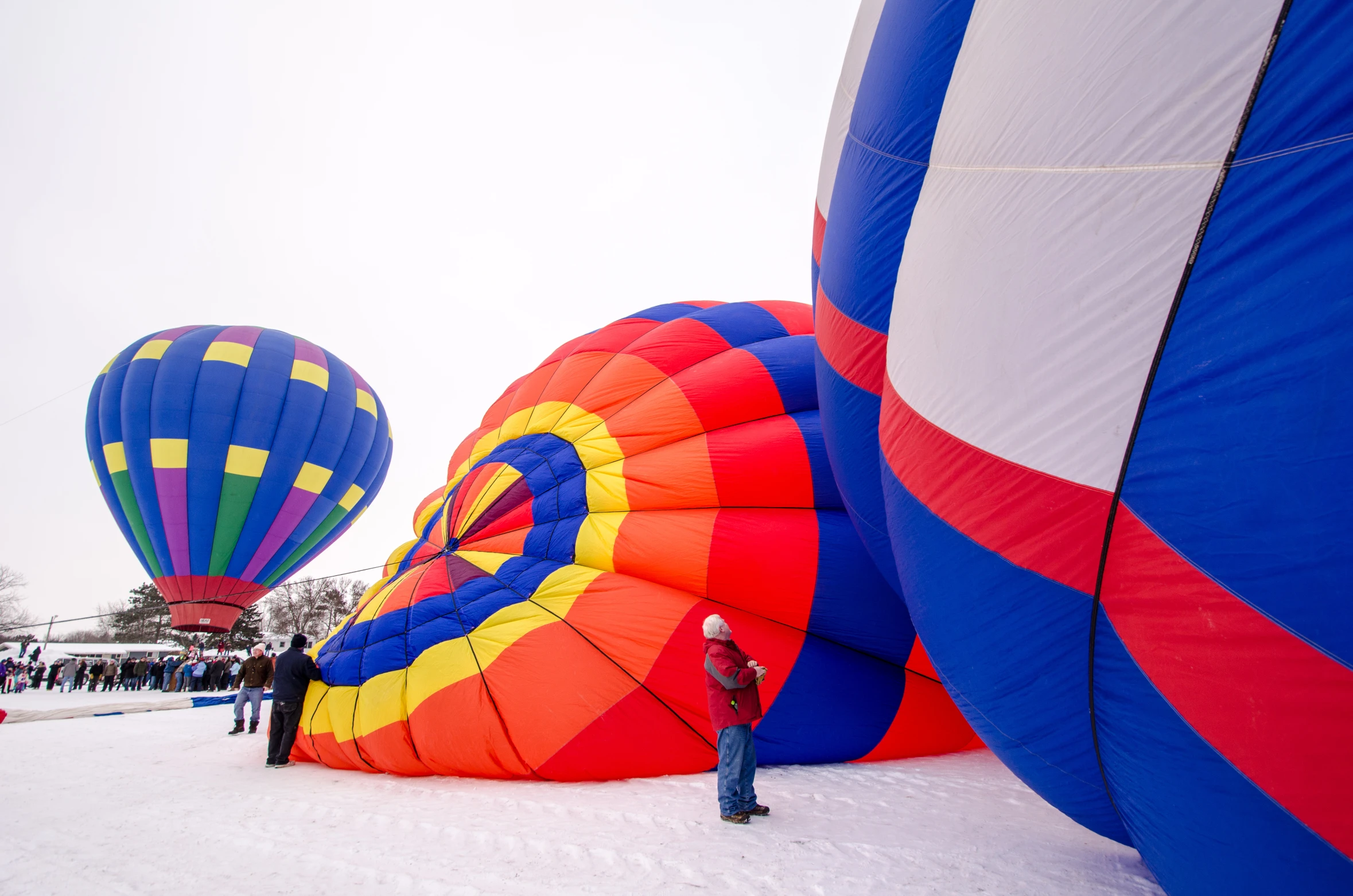 people are standing on the snow near  air balloons