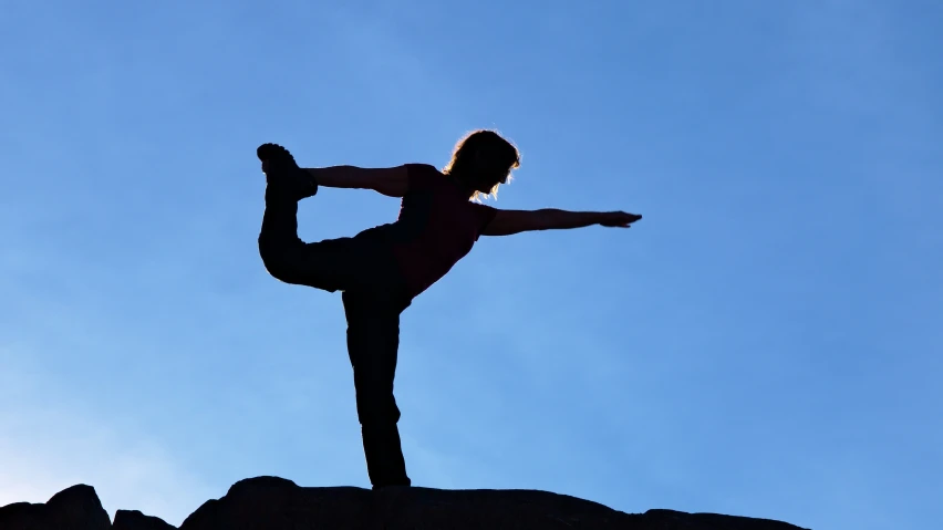 a woman is doing a back bend on a rock