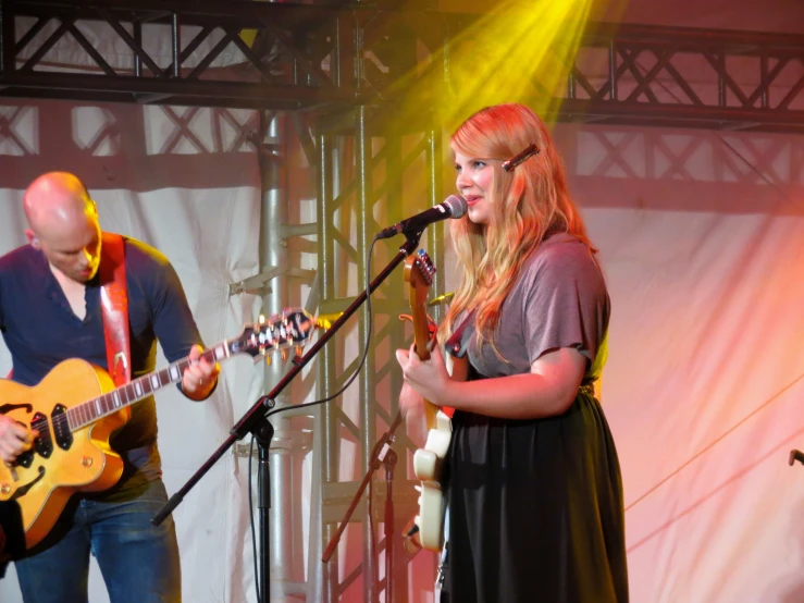 a girl playing the guitar in front of a band