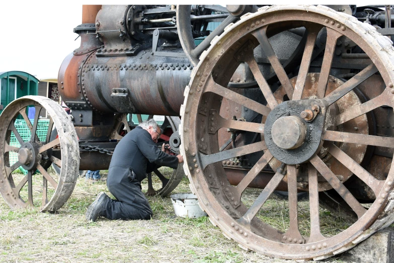 a man fixing the wheels on a large old - fashioned truck