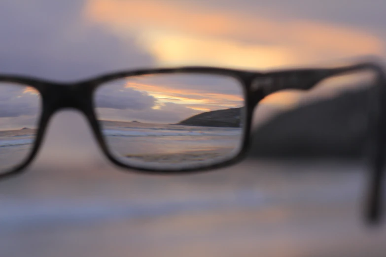 a pair of black glasses reflecting an ocean scene