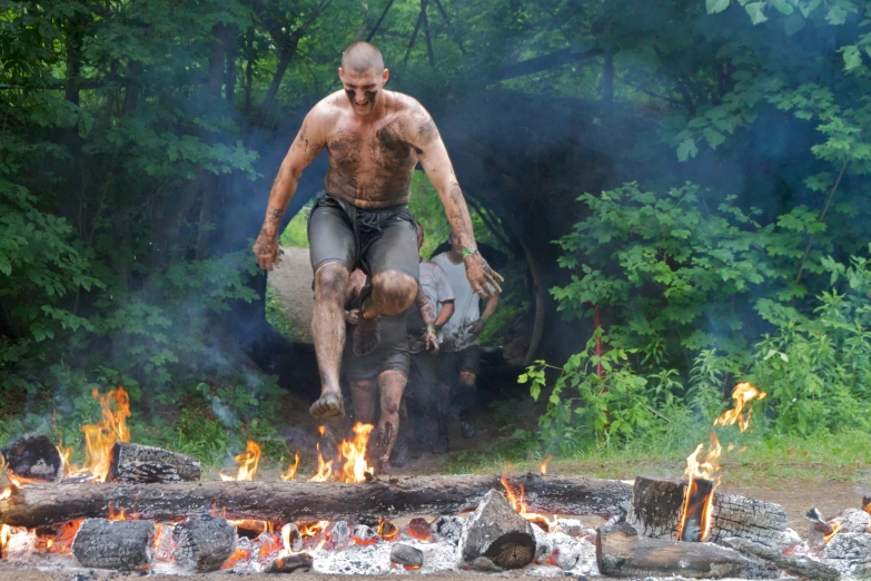 a man is riding on a fire log while another man walks near by