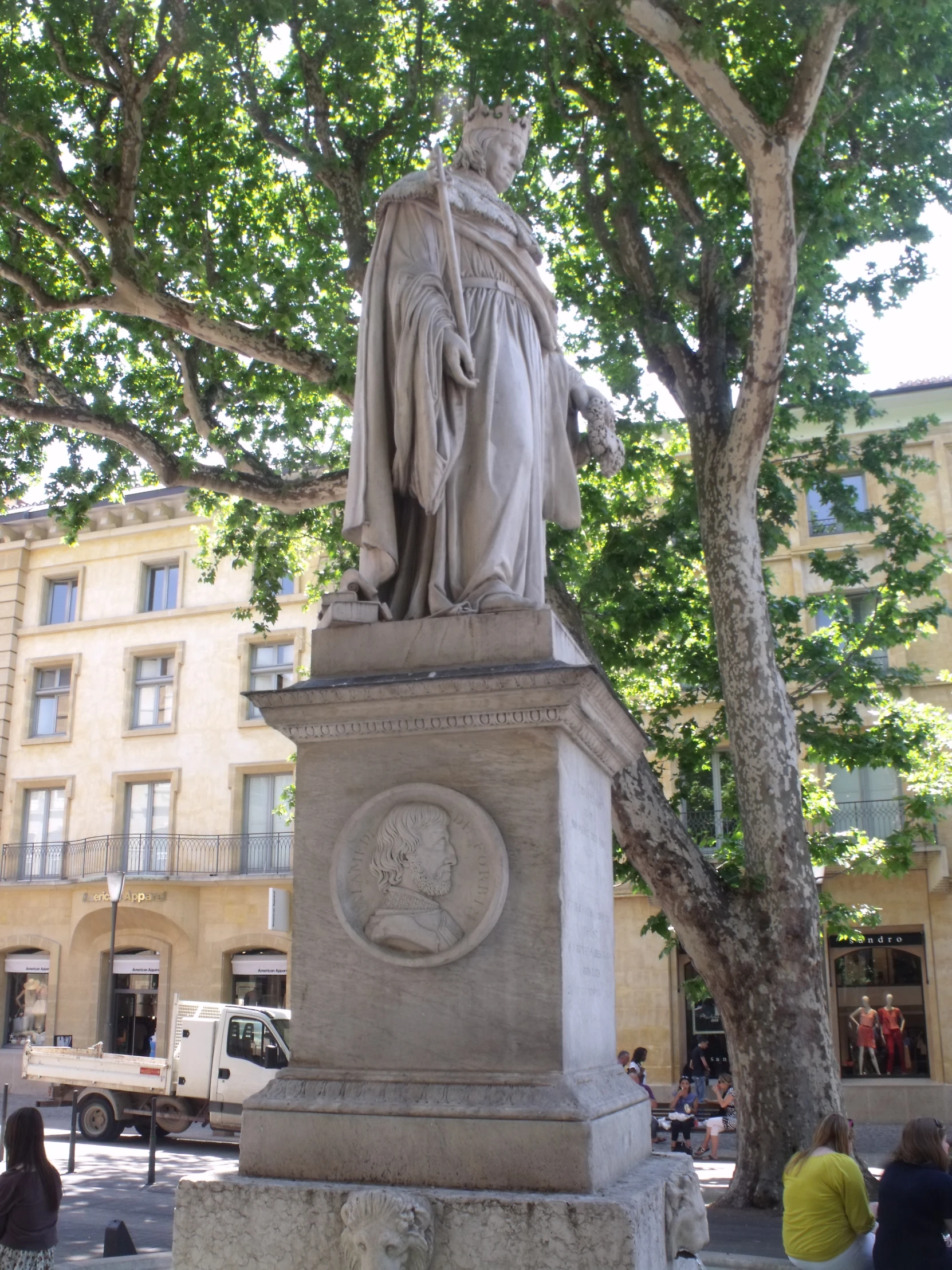 a statue on a pedestal with people gathered around it