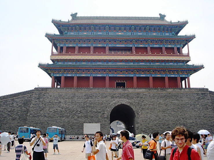 the asian gate leading to the tower has many people and people standing on it