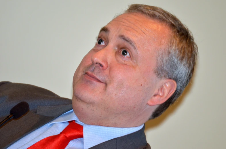 a man is standing and looking up while he has on a red tie