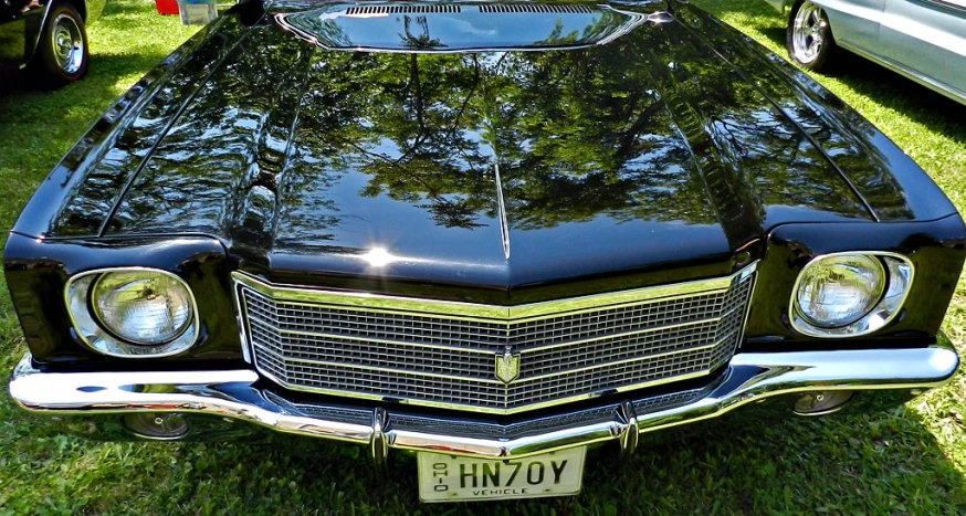 a black old fashioned car in the grass