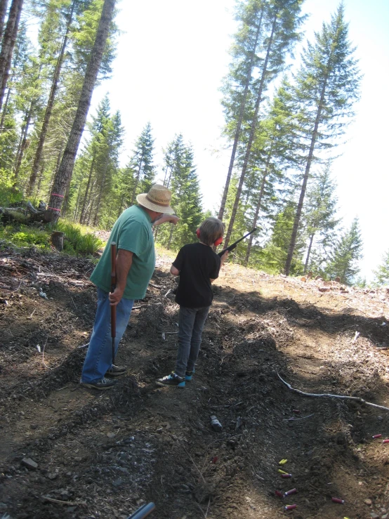 an older man and younger child are standing in the woods