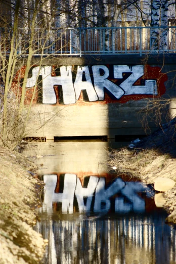 a dirty, graffiti covered bridge next to water