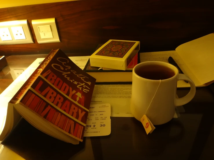 coffee and books sit on the desk next to a book and pen