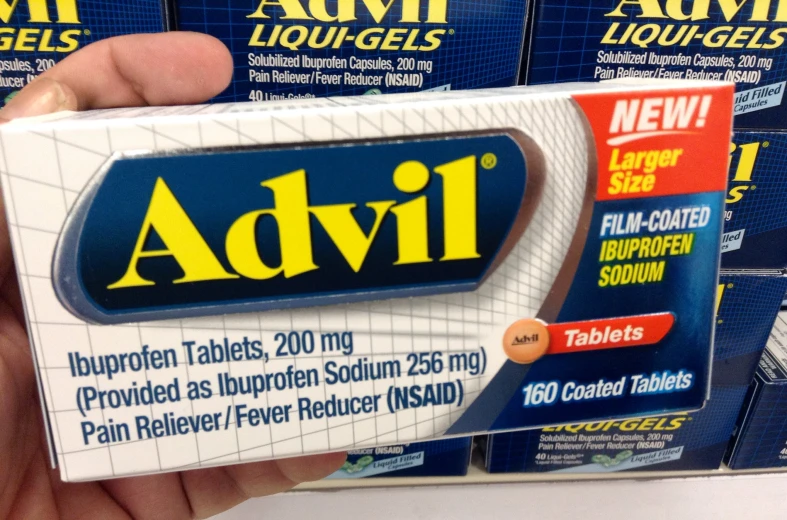 a hand holding a pack of advil tablets