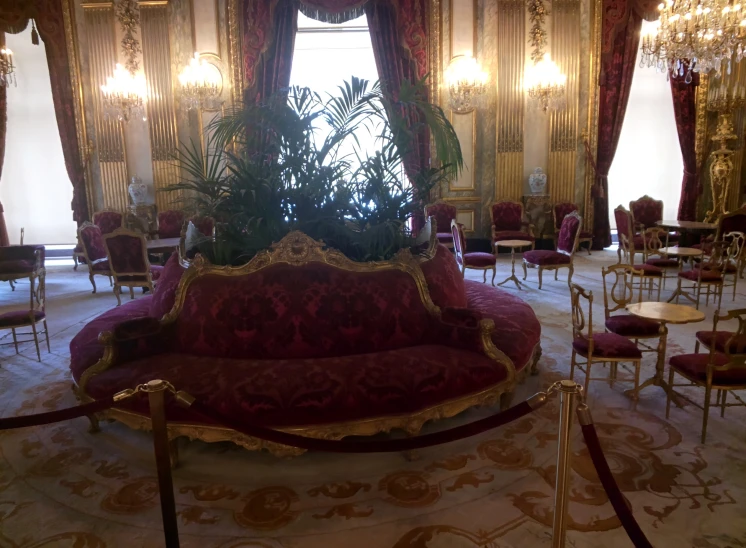 a fancy red room that has chandelier, tables, and chairs
