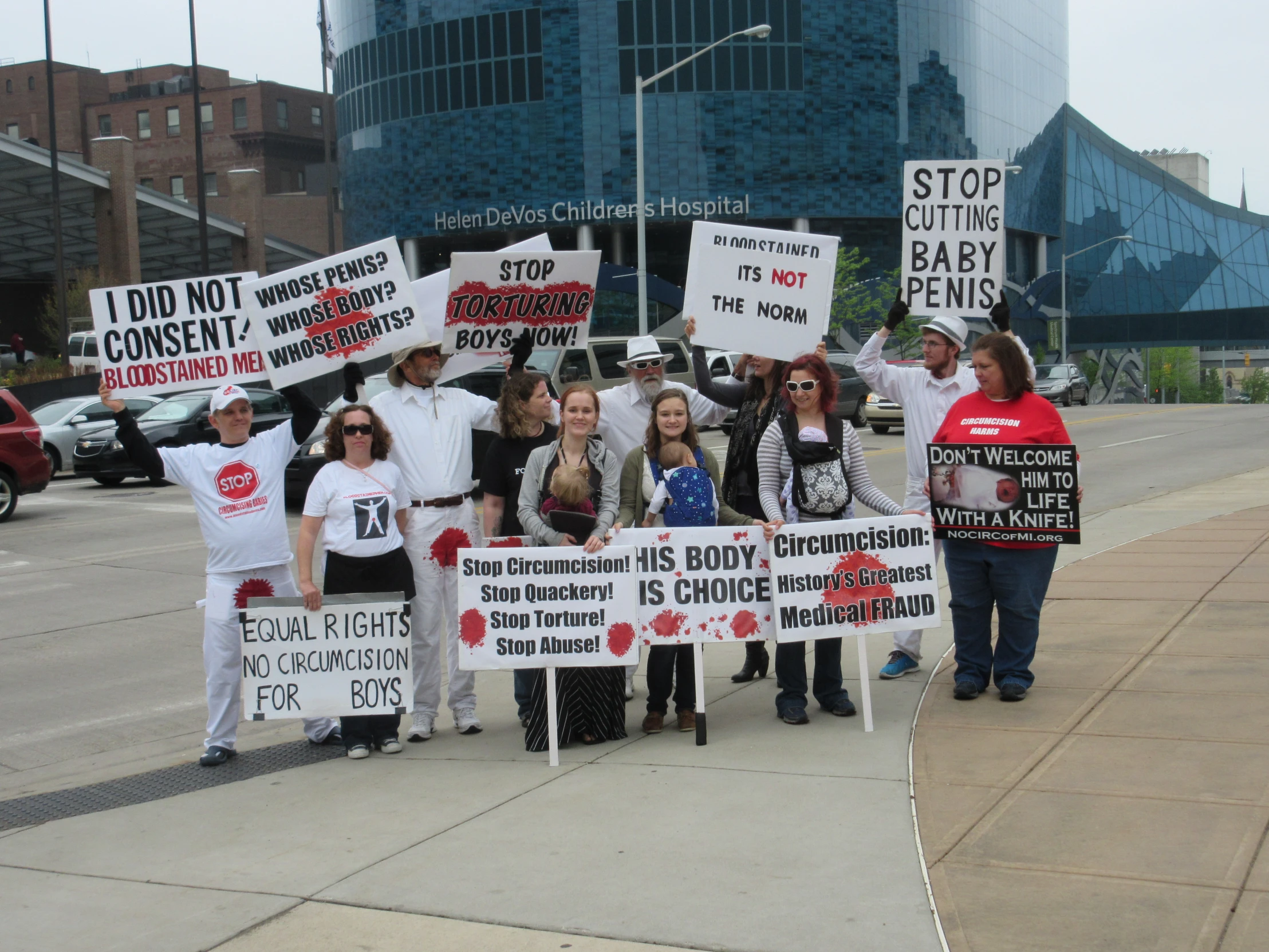 several people standing on the side of the road protesting in front of a building