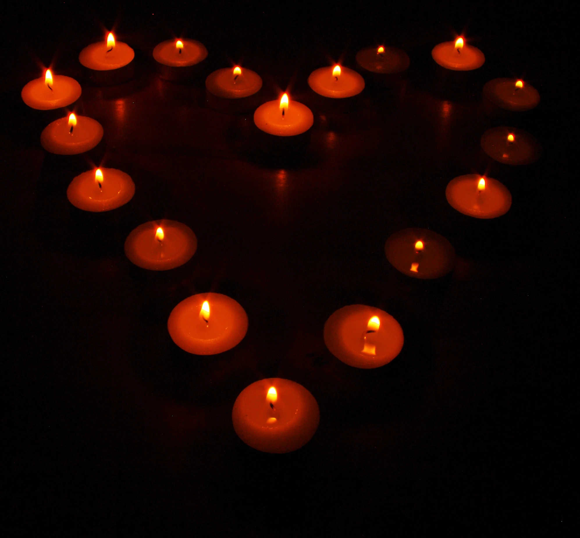 many lit candles are arranged in the shape of a heart