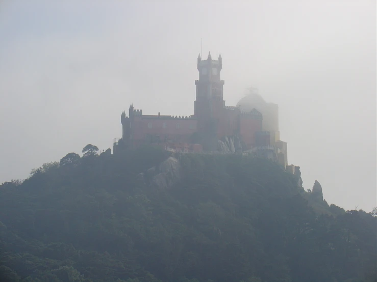 an old castle sitting on top of a green hill