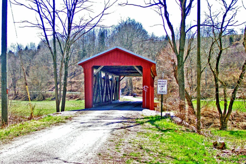 a red covered bridge next to some trees