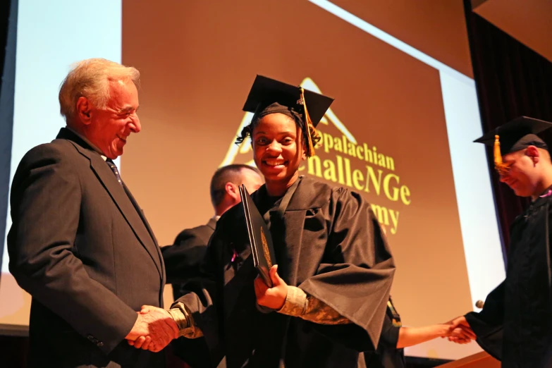 a man shaking hands with a woman at graduation