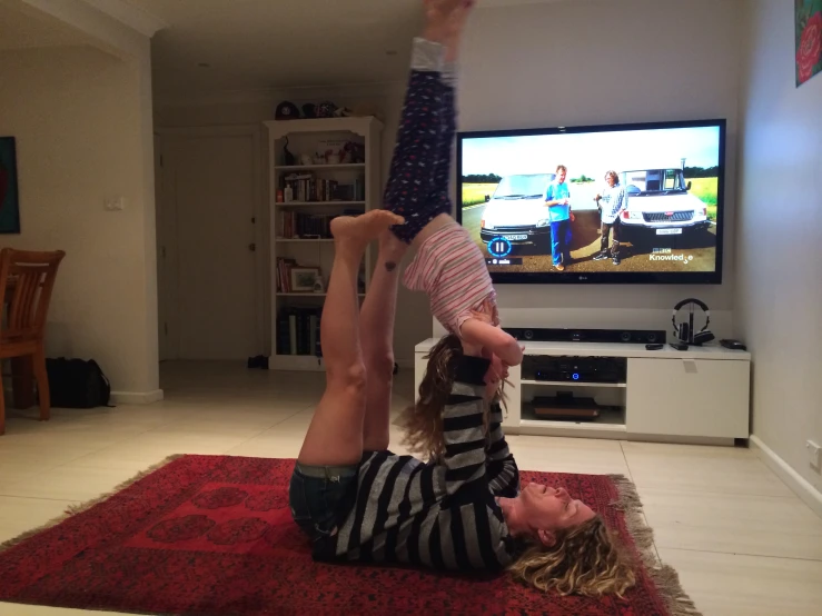 two girls are doing an acrobatic trick in front of a tv