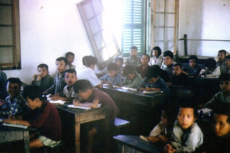 people are sitting at desks while one holds up a window