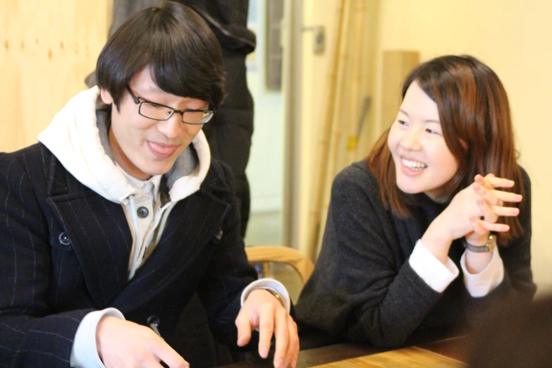 an asian couple are smiling and working on laptop computers