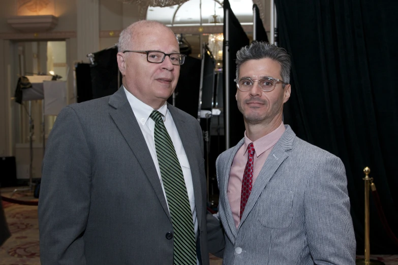 two men standing next to each other wearing neck ties