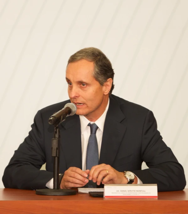 a man wearing a suit speaks in front of a microphone