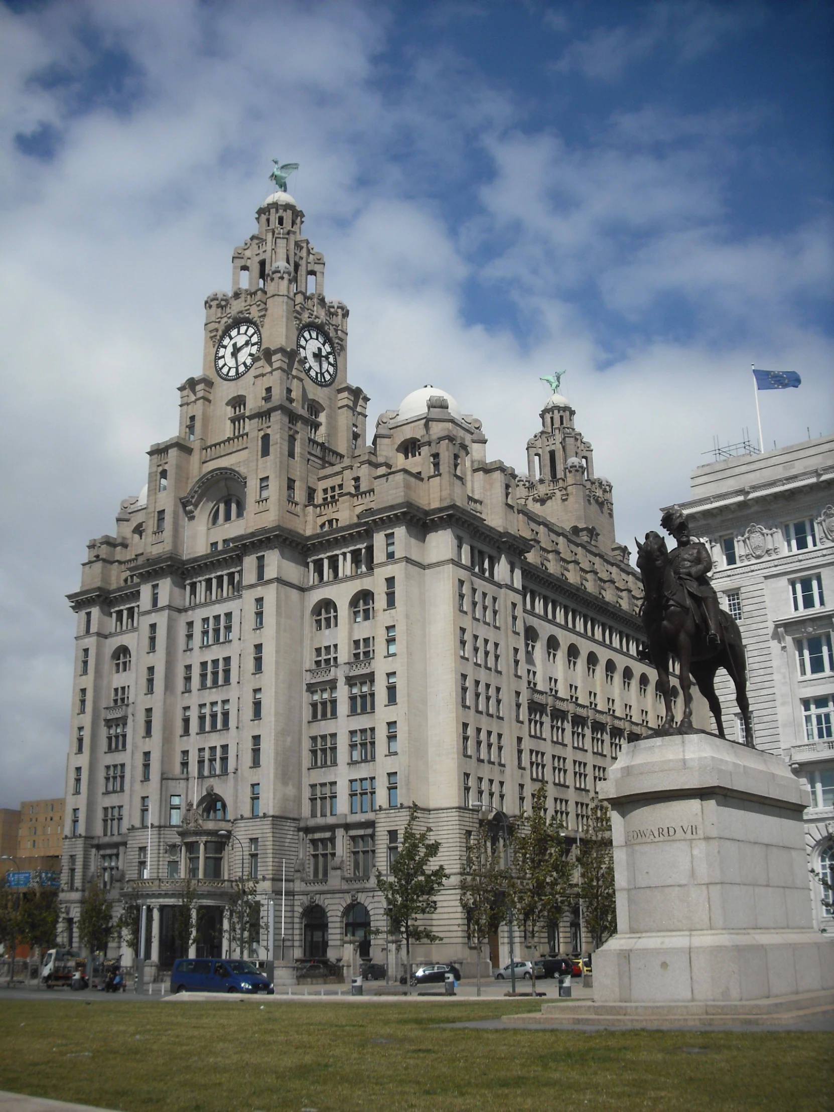 a statue of a horse with a clock on top in front of a large building