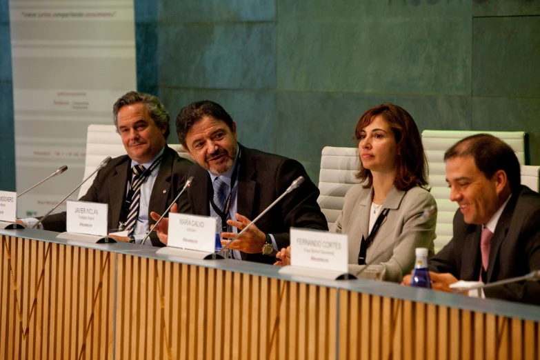 four people sitting in front of an empty meeting table