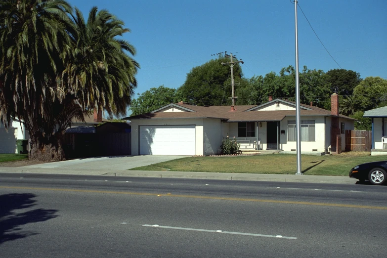 a home with a driveway, two trees, a car parked on the curb