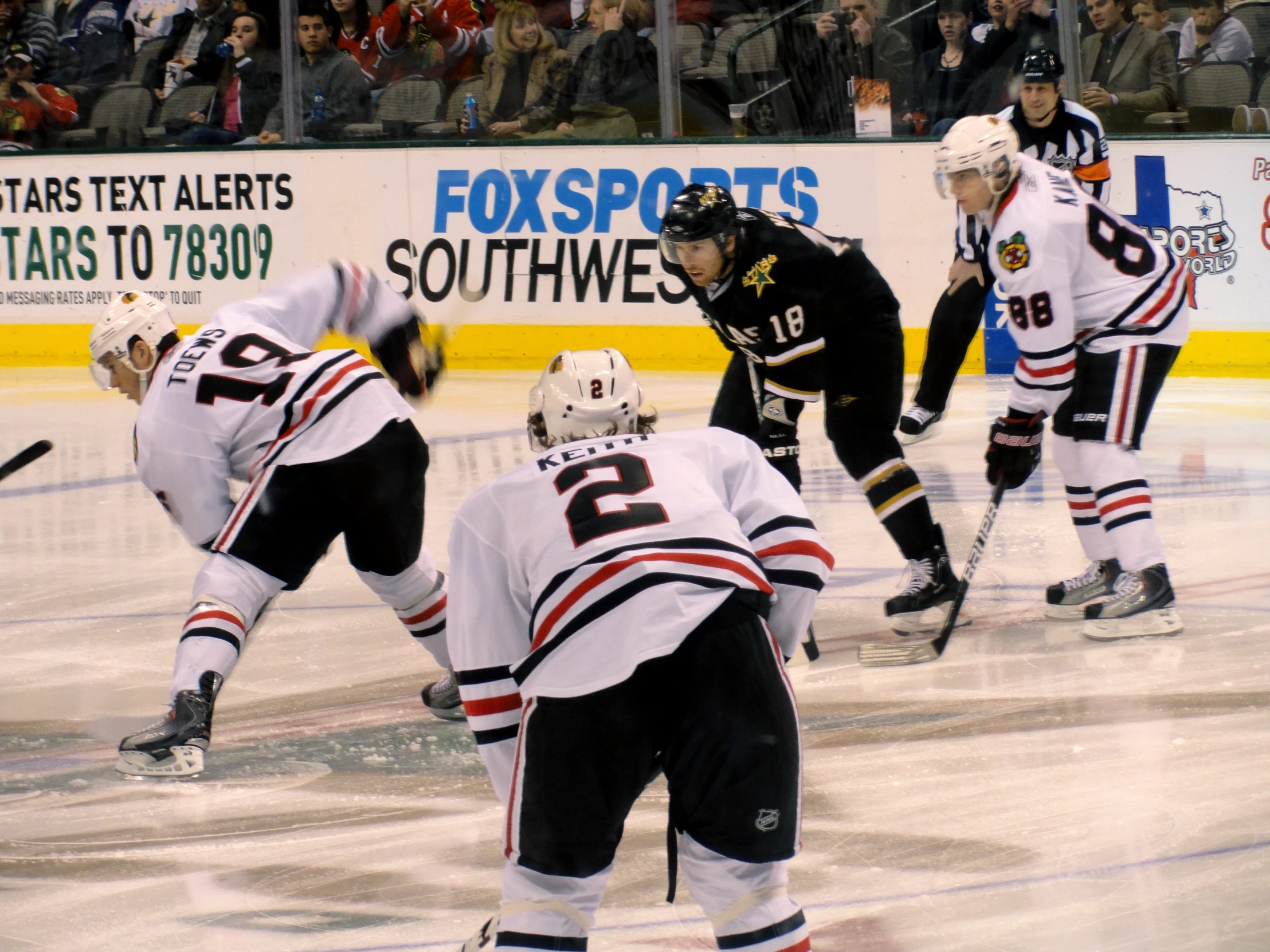 an ice hockey game is in action, with the goalie waiting for the ball