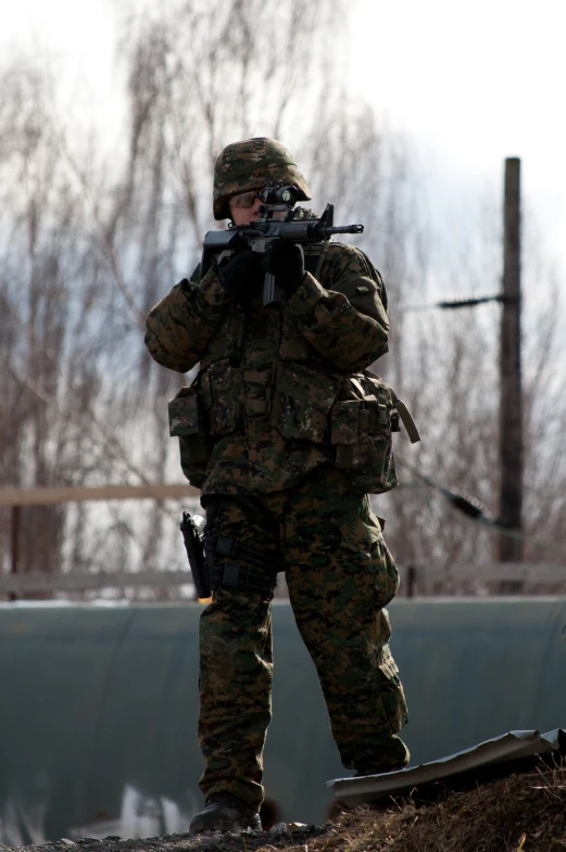 a soldier is holding a rifle on his knee