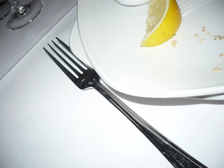 the fork is next to the plate with a half eaten lemon